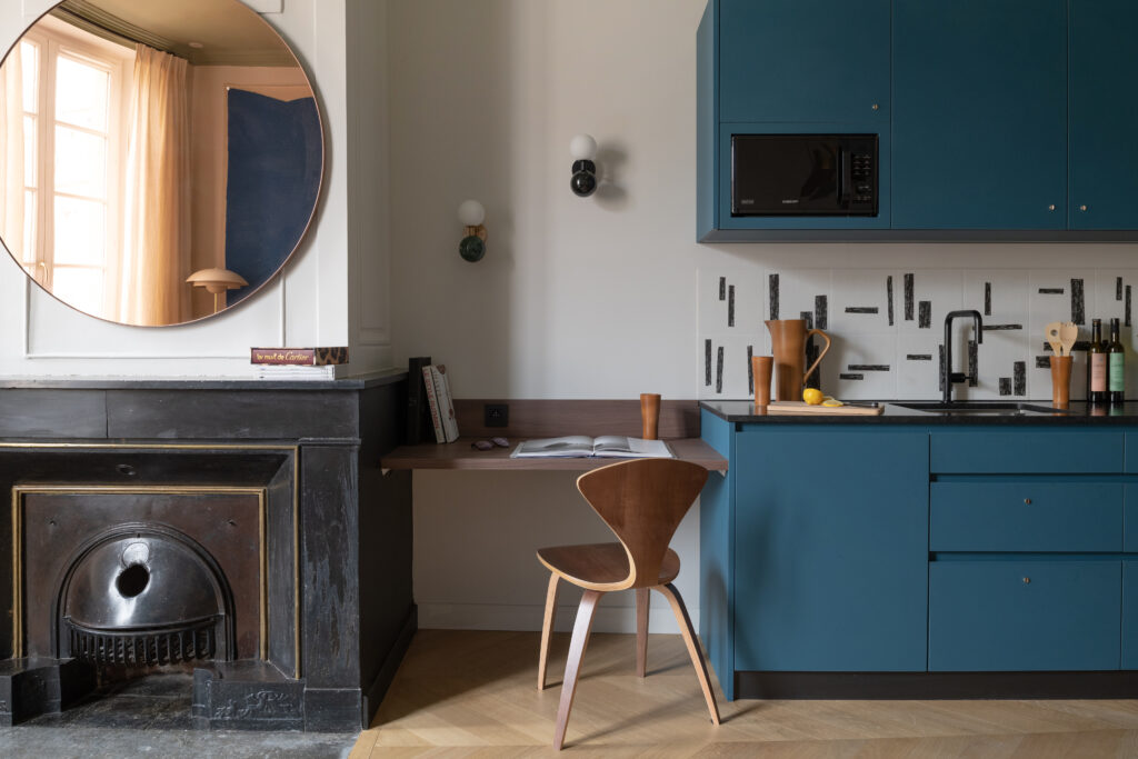 Photo de la Suite Masala à Lyon. Cheminée apparente, bureau et cuisine équipée bleue canard.